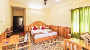 Une chambre à coucher avec un lit en bois, un bureau, une chaise, un ventilateur de plafond et un rideau vert.