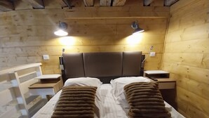 Habitación de cabaña de madera con una cama, dos mesitas de noche y dos lámparas de pared.