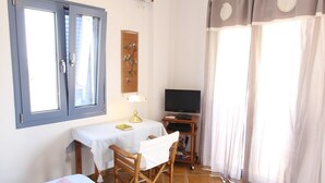 Ein Zimmer mit zwei Betten, einem Schreibtisch mit Stuhl, einem Fernseher und einem Deckenventilator.