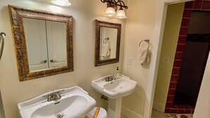 Ein Badezimmer mit zwei Waschbecken, einem Spiegel und einer Leuchte darüber.