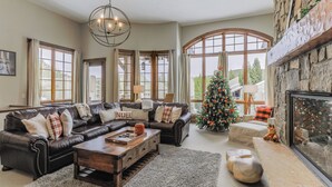 Una sala de estar acogedora con chimenea, sofás de cuero, una mesa de centro y un árbol de Navidad.