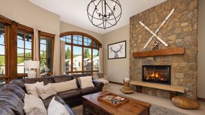 Un salón acogedor con chimenea de piedra, sofá de cuero y candelabro.