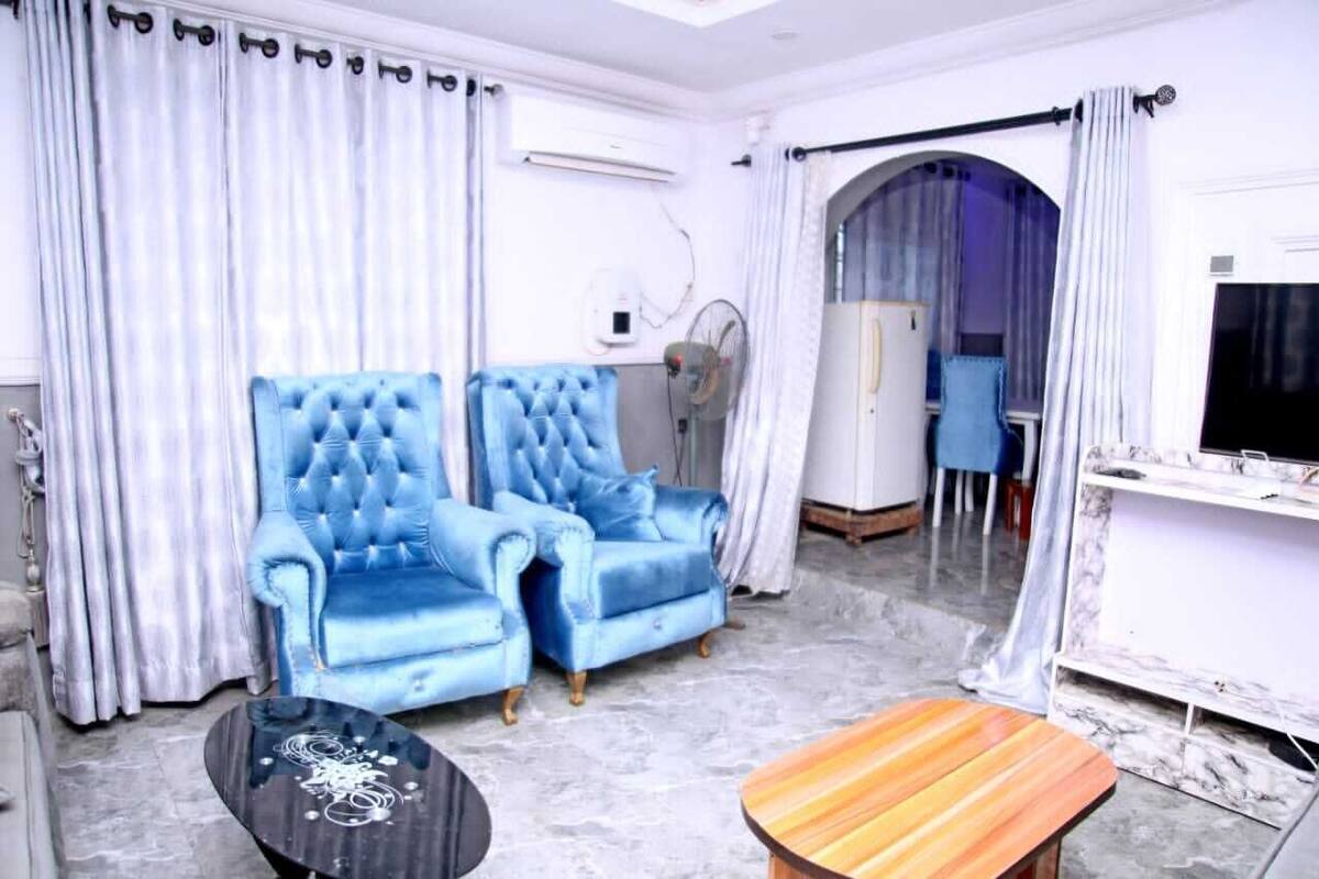 A living room with a blue sofa, a wooden coffee table, and a TV mounted on the wall.