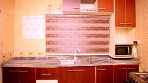 Una cocina con encimera de mármol, armarios de madera, microondas y cocina a gas.