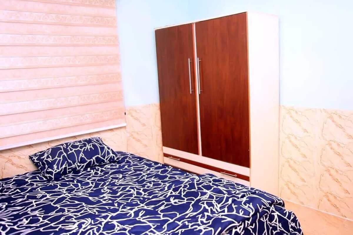 A bedroom with a bed, a wardrobe, and a window with blinds.