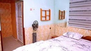 Un dormitorio con cama, ventilador y ventana con persianas.