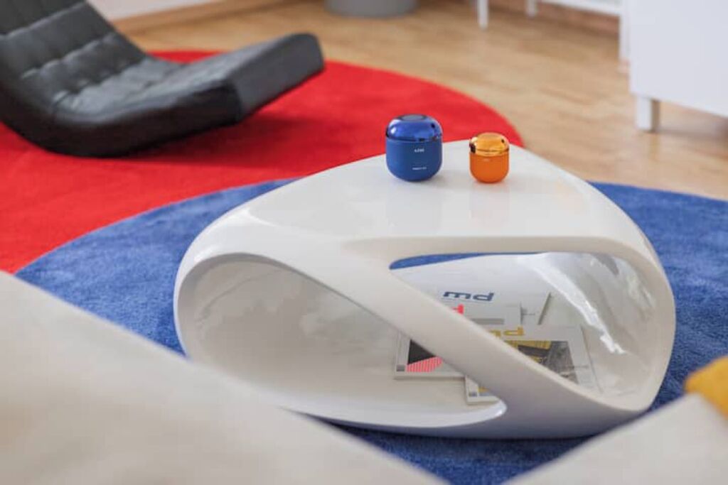 A white, modern, curved chair with a small blue and orange object on top.