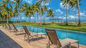A poolside area with lounge chairs and palm trees. - ORLA VILLAS - SÃO MIGUEL DOS MILAGRES (Passo de Camaragibe)