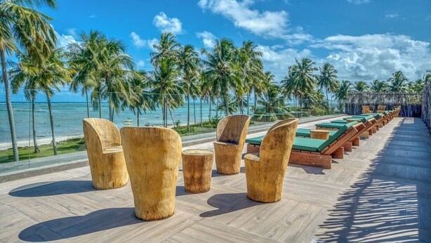 A beachside lounge area with wooden furniture and a view of the ocean. - ORLA VILLAS - SÃO MIGUEL DOS MILAGRES (Passo de Camaragibe)