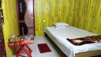 A small room with a bed, a table with a red base, and a wall with vertical wooden slats.