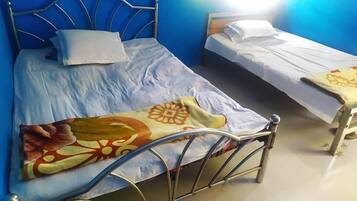 A room with two beds, one with a metal frame and the other with a wooden frame.