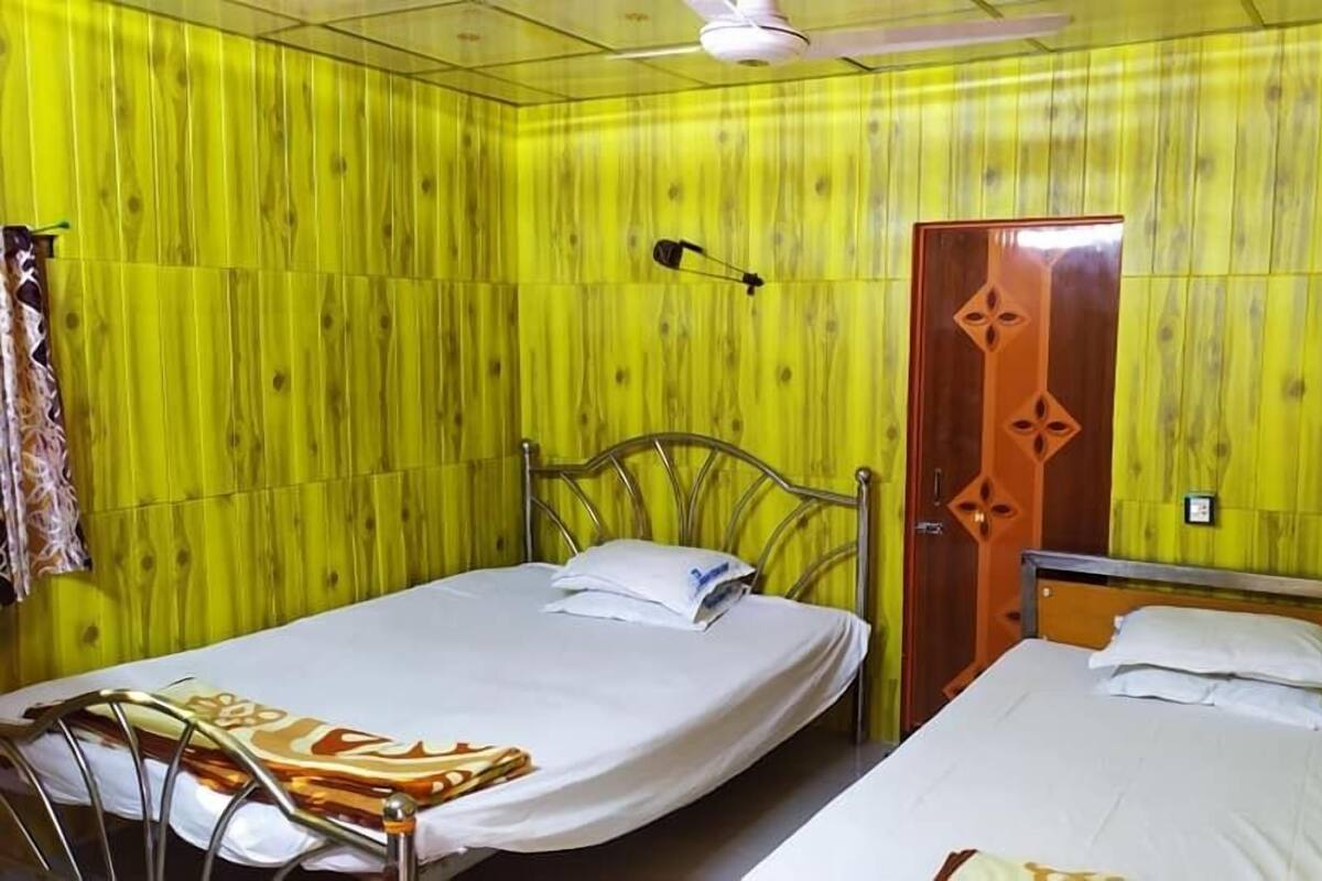 A room with two beds, a wooden door, and a ceiling fan.