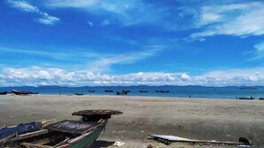 Una playa con barcos y montañas al fondo.