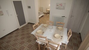 A dining area with a table set for four, surrounded by wooden chairs, a radiator, and a door. - Lavender, apartment in the heart of the historic center  (Martina Franca)