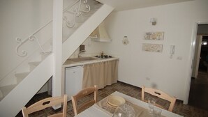 A compact kitchen with a dining area, a staircase, and a small refrigerator. - Lavender, apartment in the heart of the historic center  (Martina Franca)