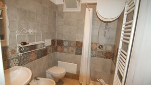 A bathroom with a toilet, bidet, sink, shower, and a towel rack. - Lavender, apartment in the heart of the historic center  (Martina Franca)