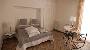 A bedroom with a bed, a bedside table with a lamp, a chair, and a radiator. - Lavender, apartment in the heart of the historic center  (Martina Franca)