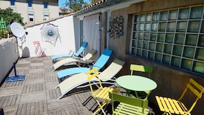 Une terrasse avec des chaises longues et une table, une antenne parabolique et un mur décoratif.