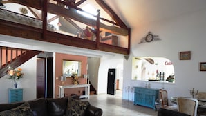 Un vaste salon doté d’un haut plafond, d’un escalier et d’un coin repas avec un buffet bleu.