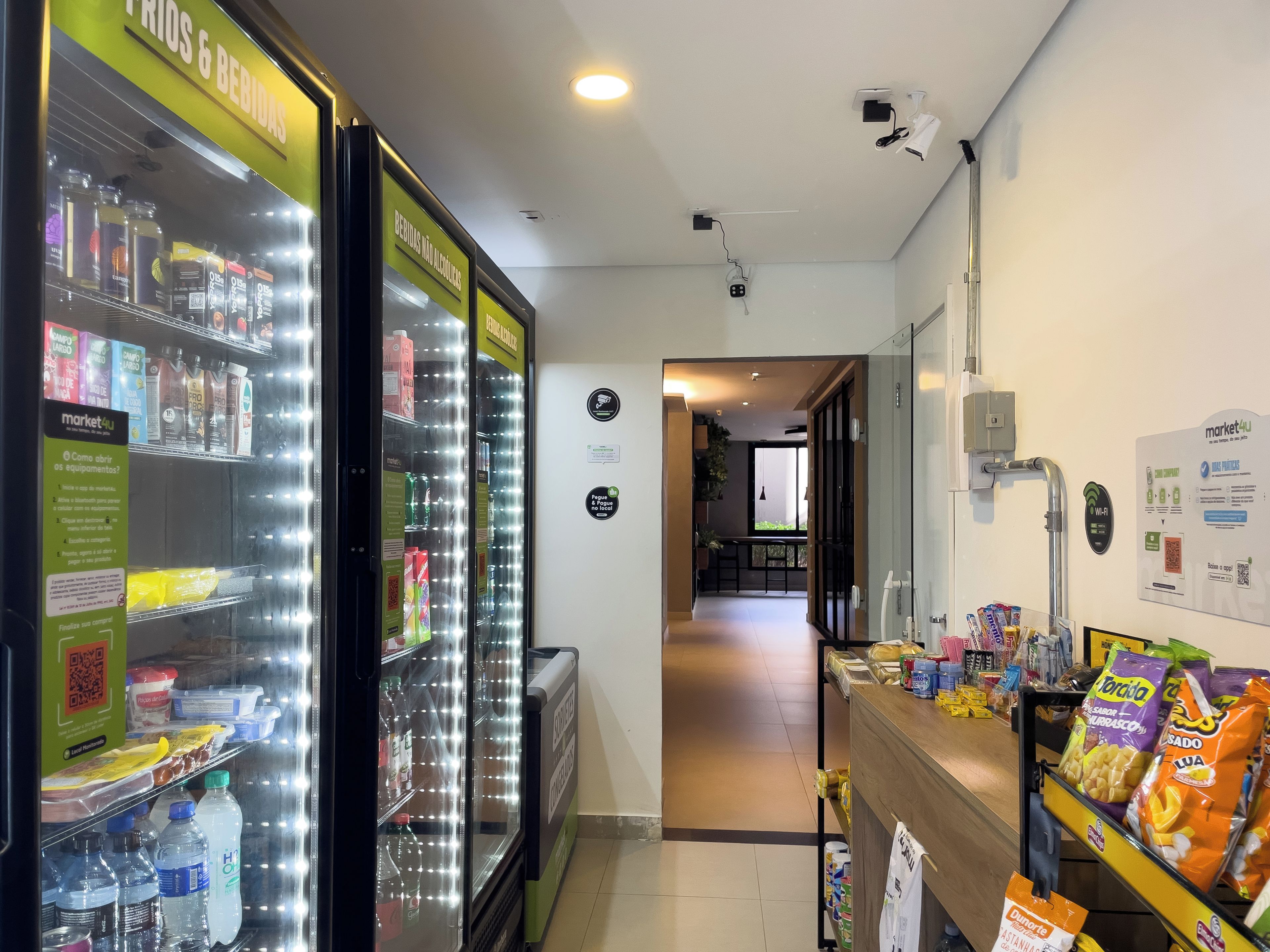 Un pasillo con una máquina expendedora a la izquierda y un bar de aperitivos a la derecha, que conduce a una zona de estar.