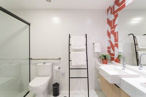 A modern bathroom with a toilet, bidet, and a sink with a mirror. - Green Load Saúde (São Paulo)