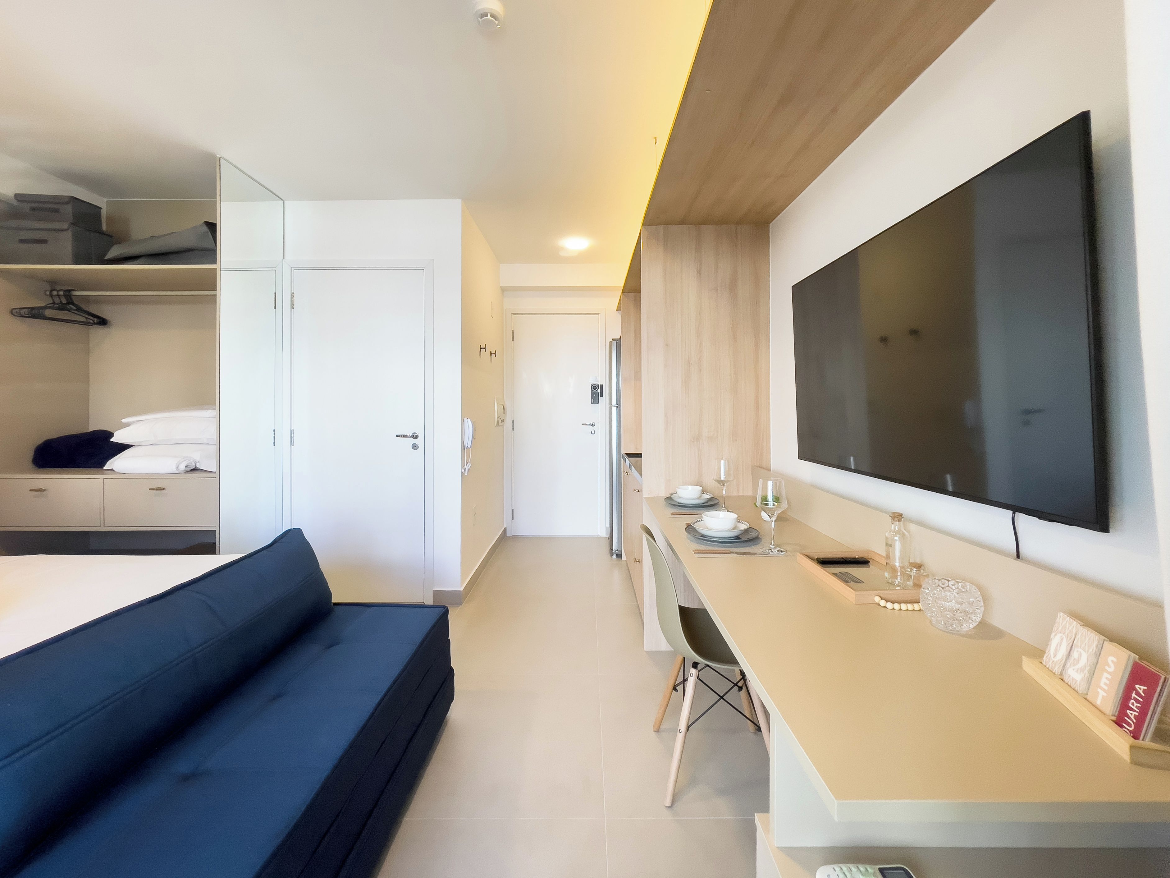 Ett modernt hotellrum med en säng, ett skrivbord och en stor TV.