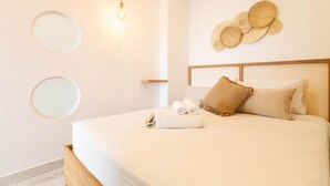 A neatly made bed with a wooden headboard, a wall-mounted mirror, and a light fixture.