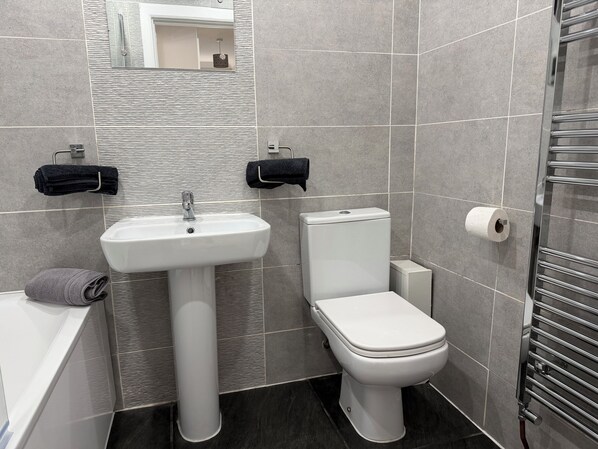 A bathroom with a white sink, toilet, and towel rack.