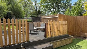 A wooden deck with a built-in bench and a small set of steps leading to a grassy area. - Cozy Maisonette in Langley Vale  (Epsom)