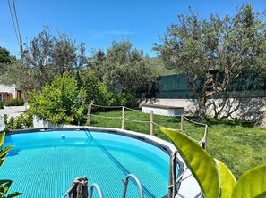 A swimming pool surrounded by greenery and a stone wall.