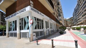 A hostel with a modern facade, large windows, and a clear sky. - Hostel Dos Estaciones (Alicante)