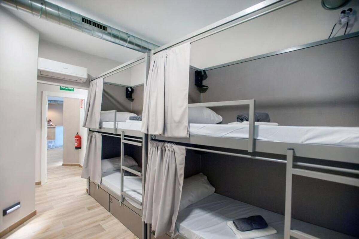 A bunk bed room with a door labeled "SALIDA" and a fire extinguisher on the wall.