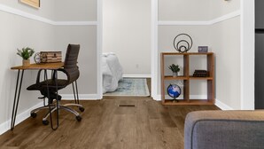 A room with a desk, office chair, bookshelf, and a white door leading to a bathroom. - Rooms on Rose (Birmingham)