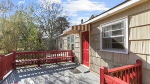 A wooden deck with a red bench, a red door, and a window. - Rooms on Rose (Birmingham)