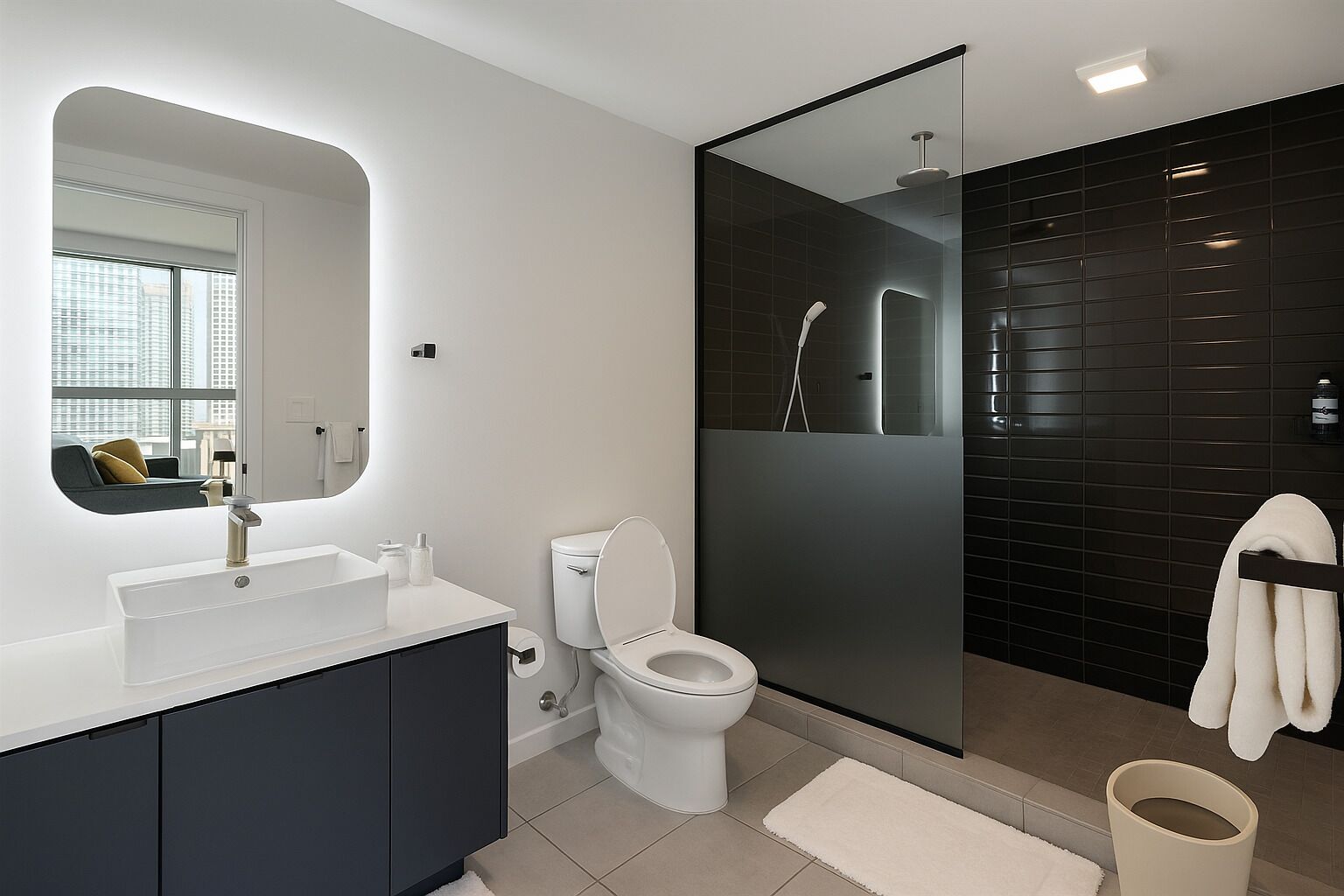 Ein modernes Badezimmer mit Waschbecken, Toilette, einer Duschkabine und einem großen Spiegel.