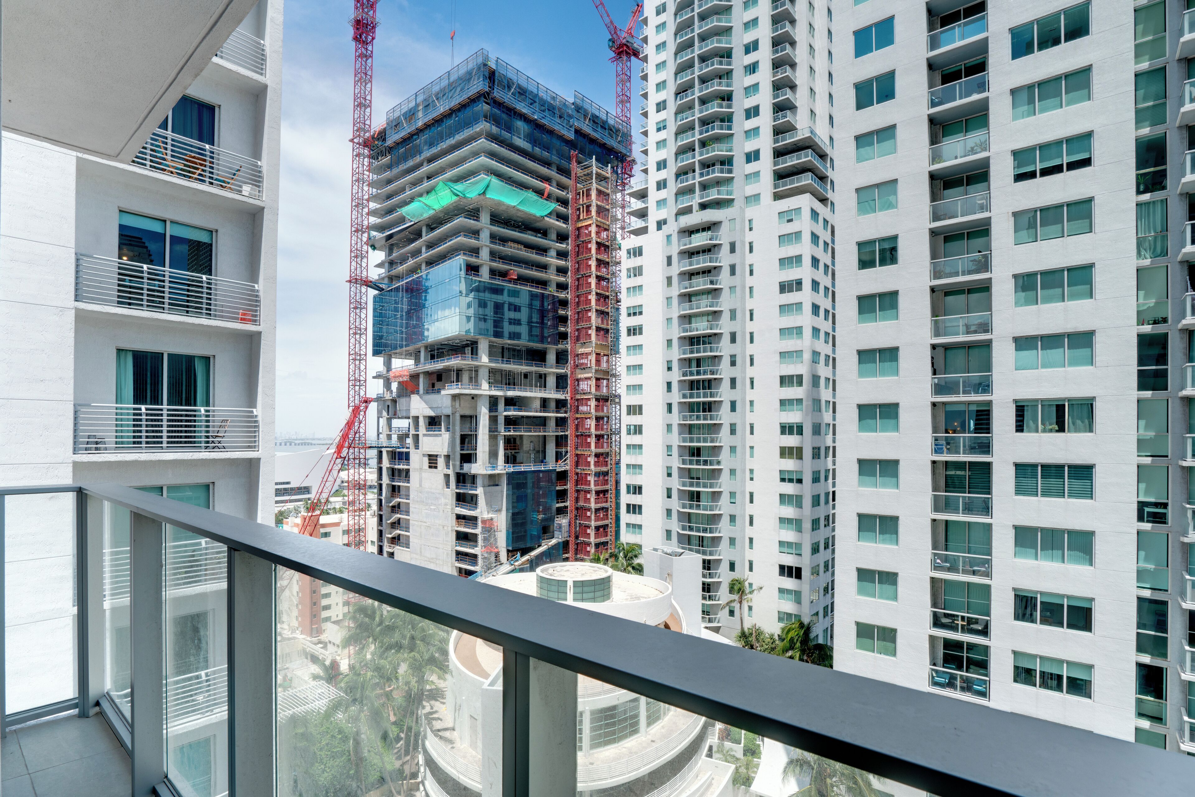 A modern high-rise building with multiple balconies and a construction crane in the background.