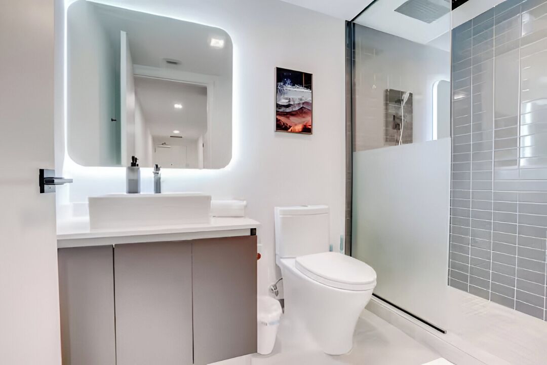 Une salle de bain moderne avec un lavabo blanc, des toilettes et une douche à parois de verre.