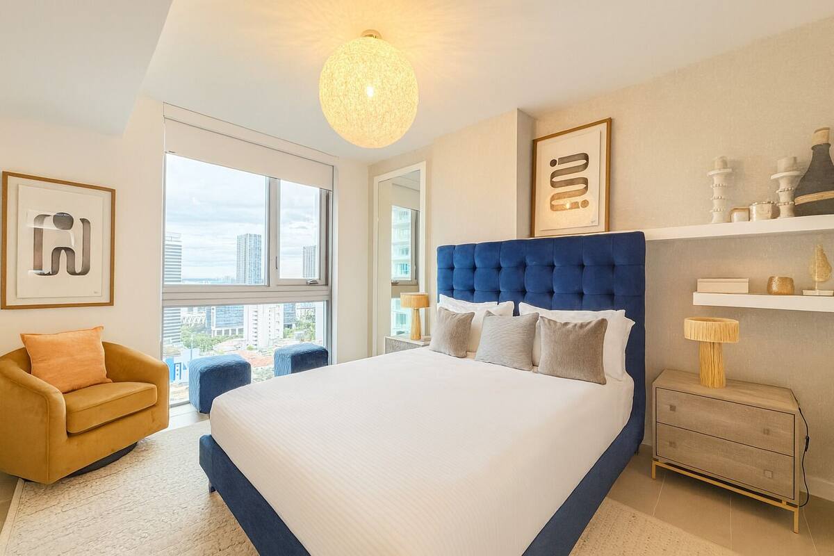 A modern bedroom with a large bed, a sofa, and a nightstand.