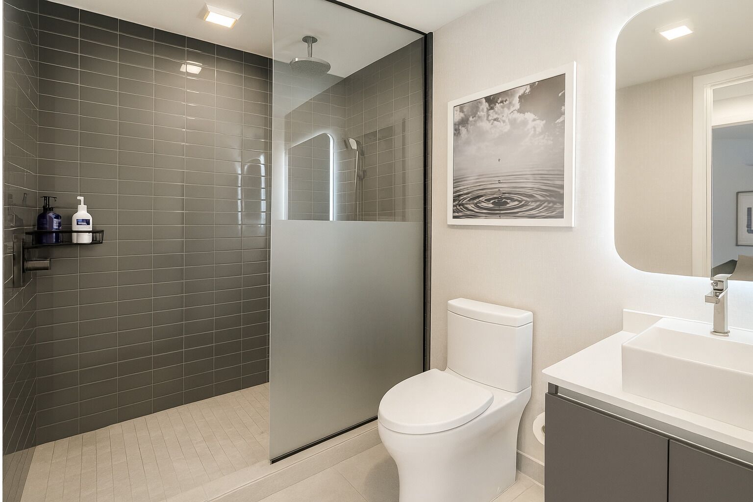 Une salle de bain moderne avec une douche à parois de verre, des toilettes, un lavabo et un tableau encadré au mur.