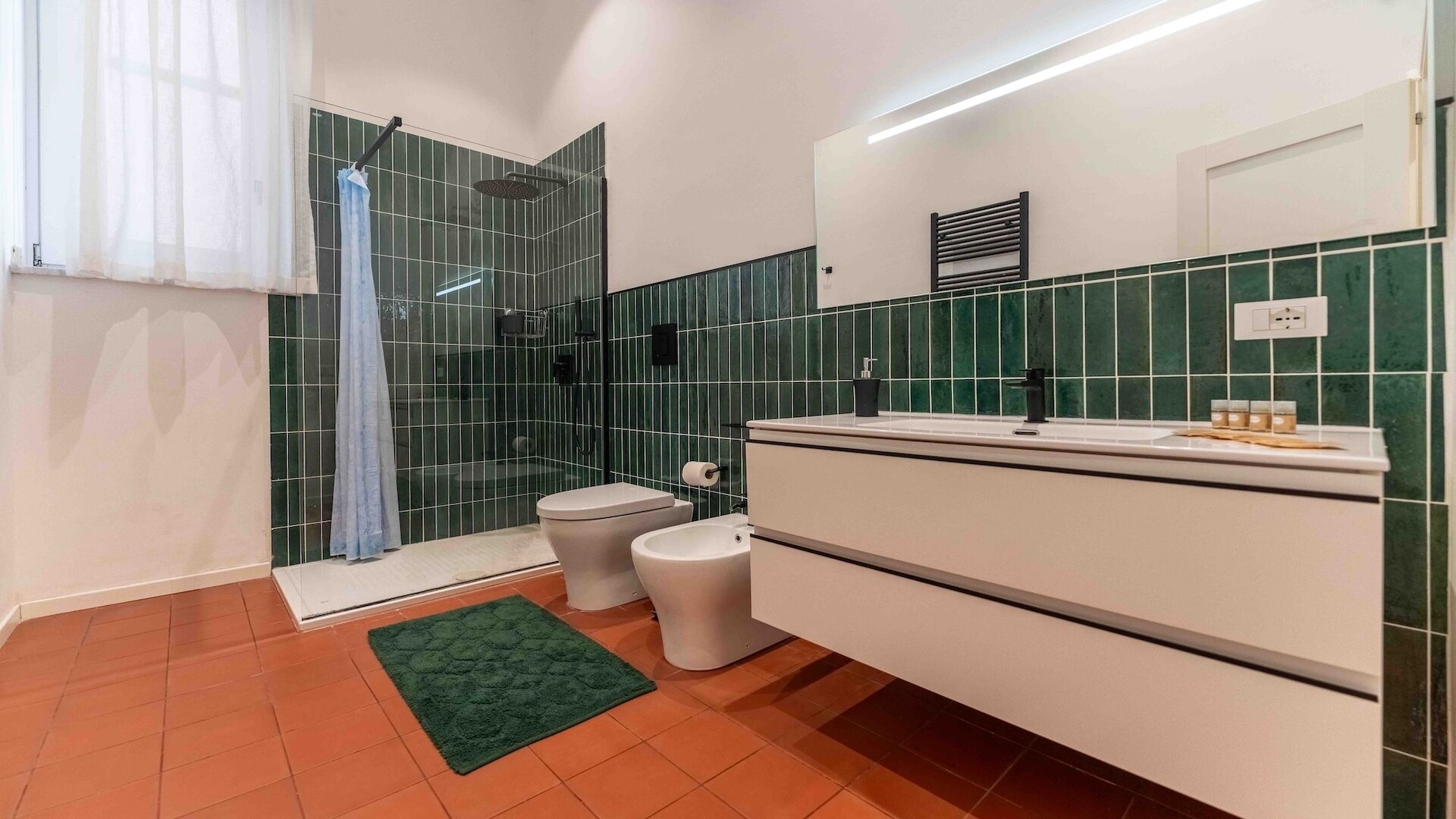 A modern bathroom with a shower, toilet, bidet, and a vanity with a mirror.