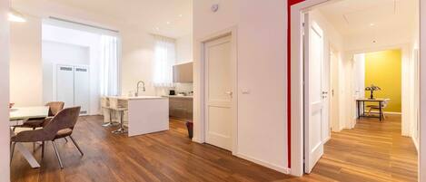 Ein modernes Apartment mit Essbereich, Küche und einem Flur, der zu einem weiteren Raum führt.