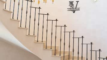 A spiral staircase with black balusters and beige steps, leading to an upper level.