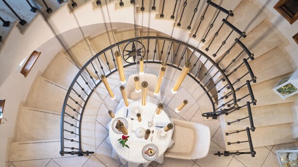 Eine Wendeltreppe mit einem zentralen Tisch, der Kerzen und eine Rose zeigt.