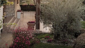 Ein Haus mit überdachter Veranda, Steinstufen und einem Garten mit blühenden Pflanzen.