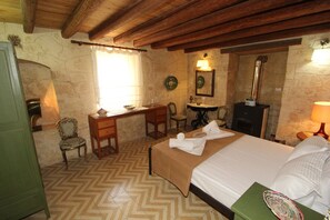 A room with a bed, a desk, a chair, a mirror, and a fireplace.
