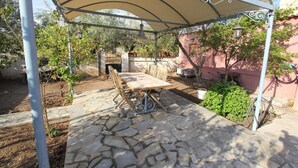 A covered patio area with stone flooring, a table and chairs, and a pergola overhead. - Kipseli s Stone House by Frangki (Aegina)