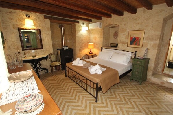 A bedroom with a bed, bedside table, lamp, and a mirror.