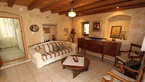 A cozy living room with a sofa, wooden chairs, a coffee table, and a fireplace. - Kipseli s Stone House by Frangki (Aegina)