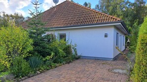 Une maison de plain-pied, dotée d’un toit en tuiles et entourée d’une végétation luxuriante.