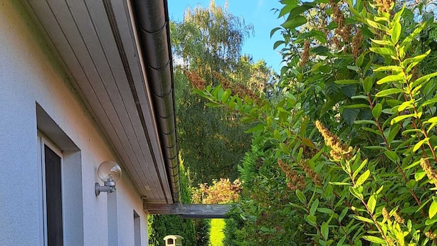 Un étroit sentier pavé de briques mène à un bâtiment doté d’une cheminée et bordé d’un petit jardin.